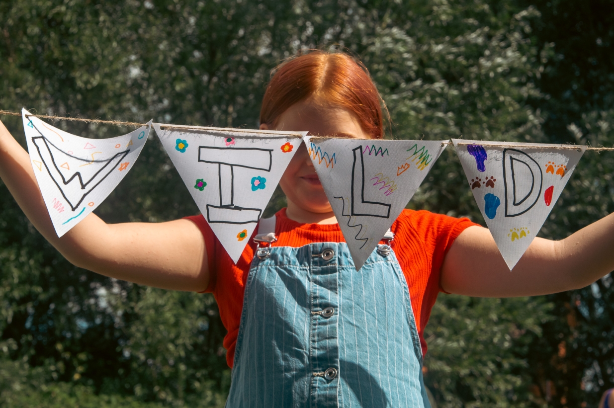 A girl holding 'wild' bunting.